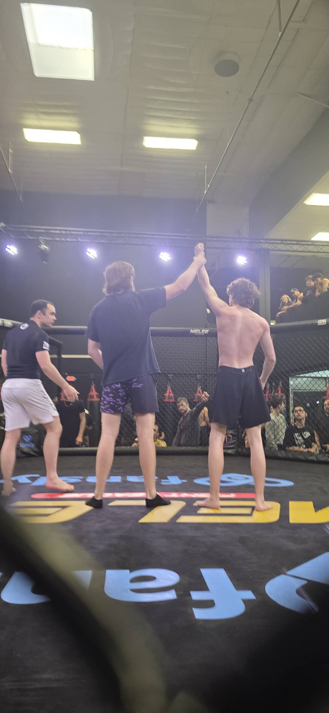 Martial Arts of Waco student holding arm up in victory after winning MMA sparring match.